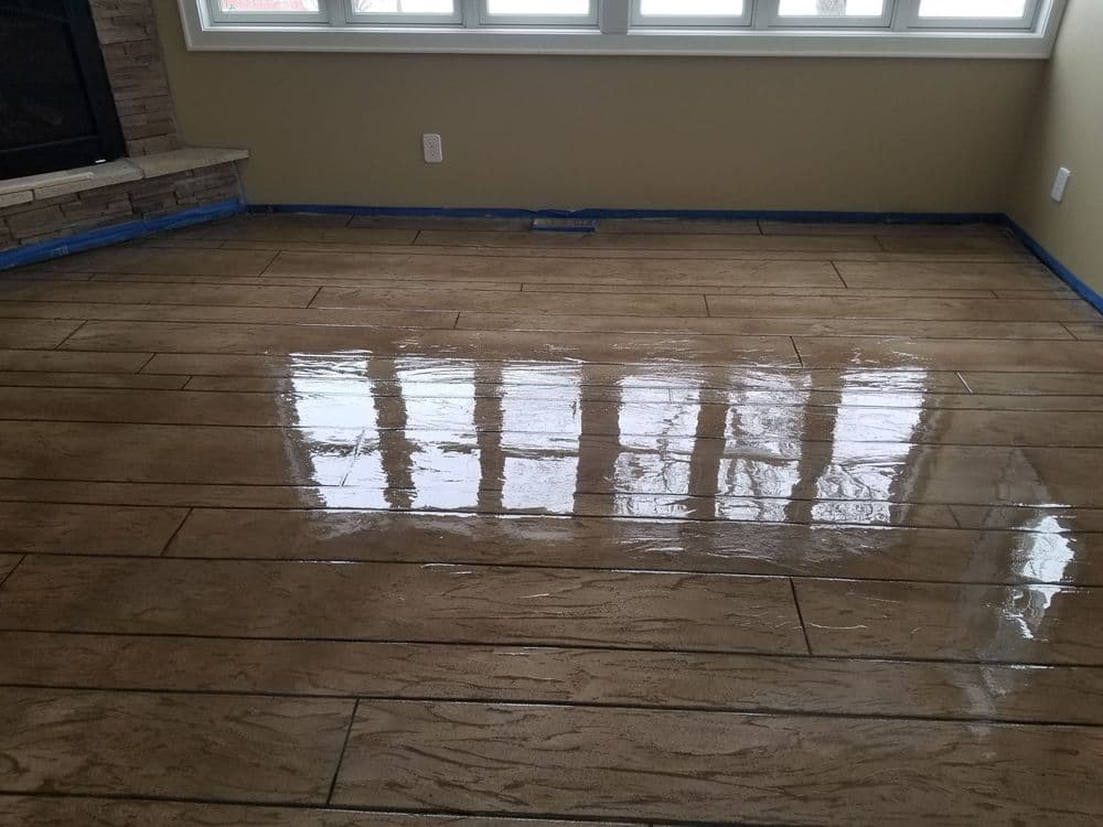 Glossy stained concrete floor in living room with large windows and fireplace.