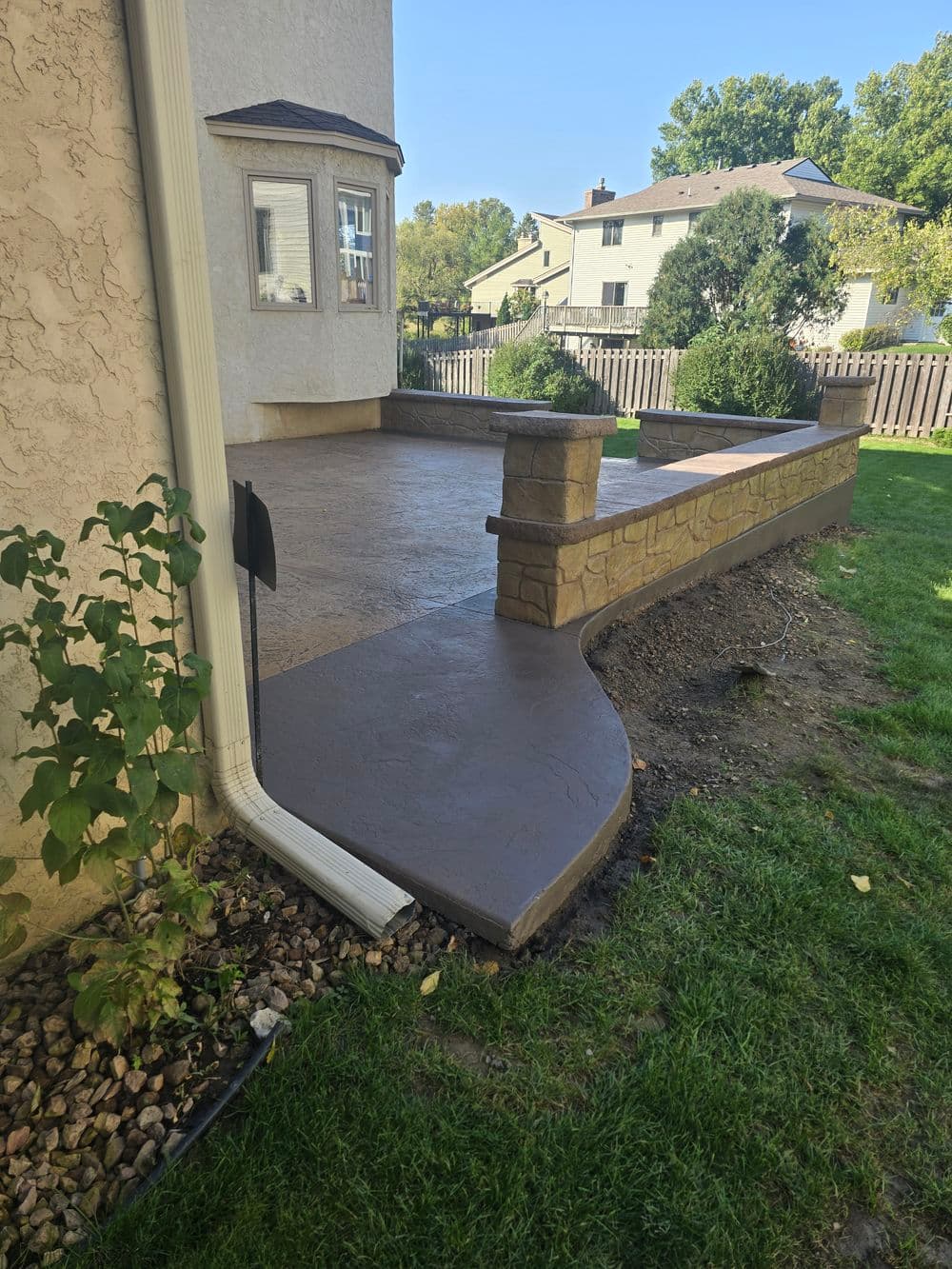 Newly poured decorative concrete patio with stone edging in a residential backyard.